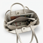 Beige handbag with items inside on a white background